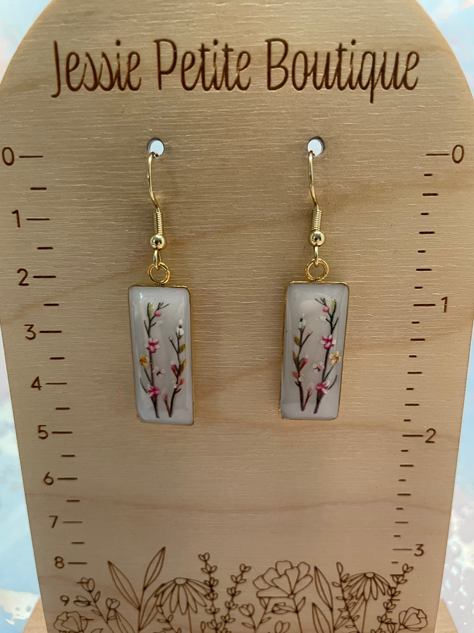 Pair of floral earrings on a wooden display card with 'Jessie Petite Boutique' branding.