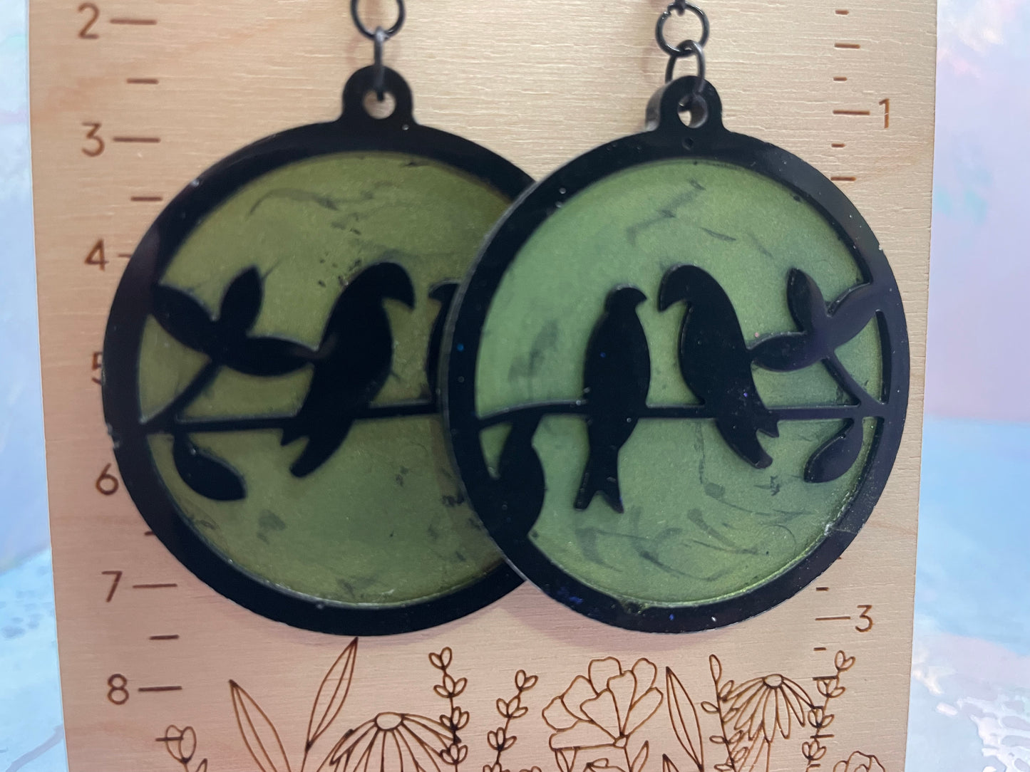 Pair of earrings with bird design on a wooden stand