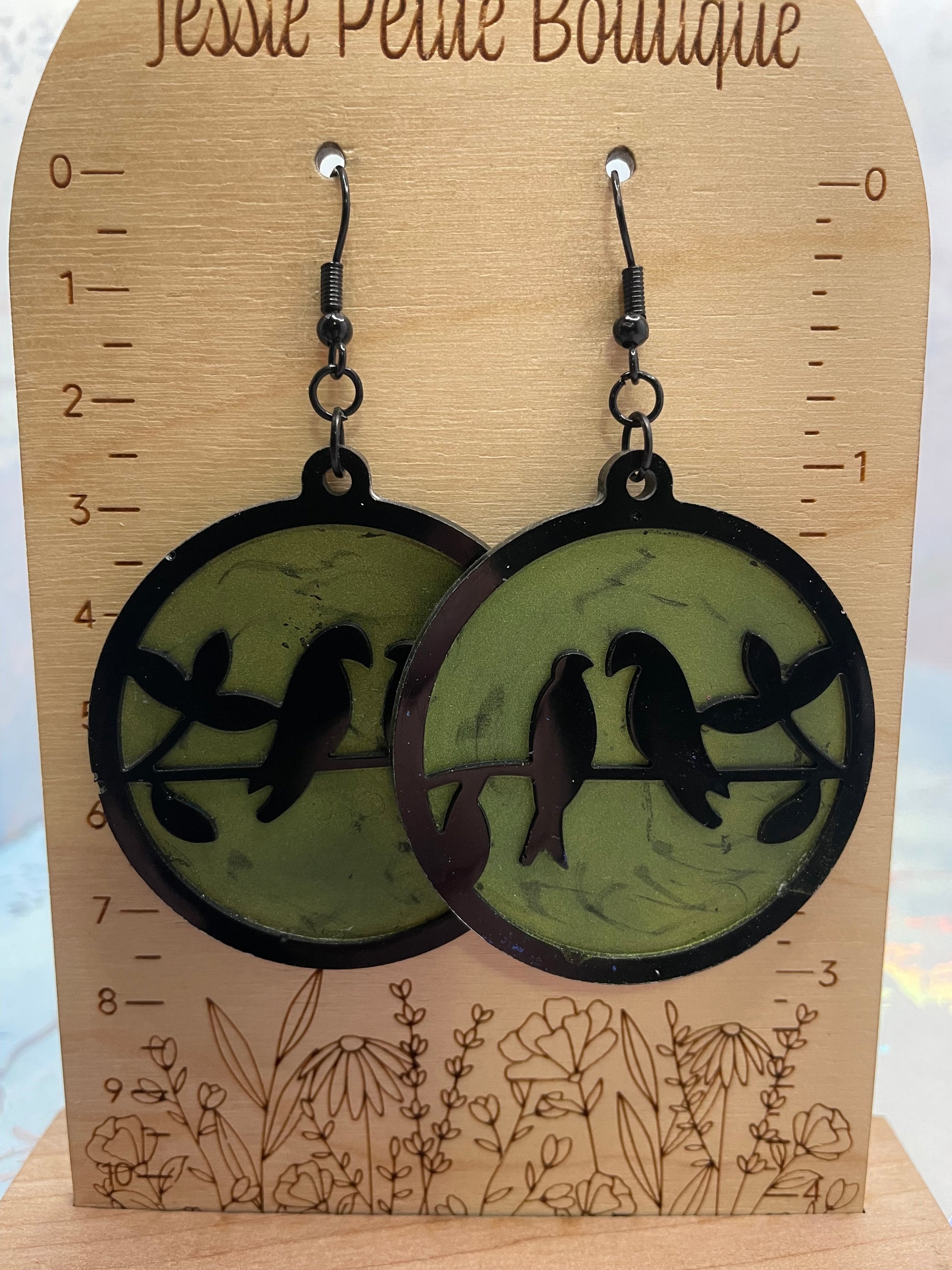 Pair of earrings with bird design on a wooden display card with measurements.