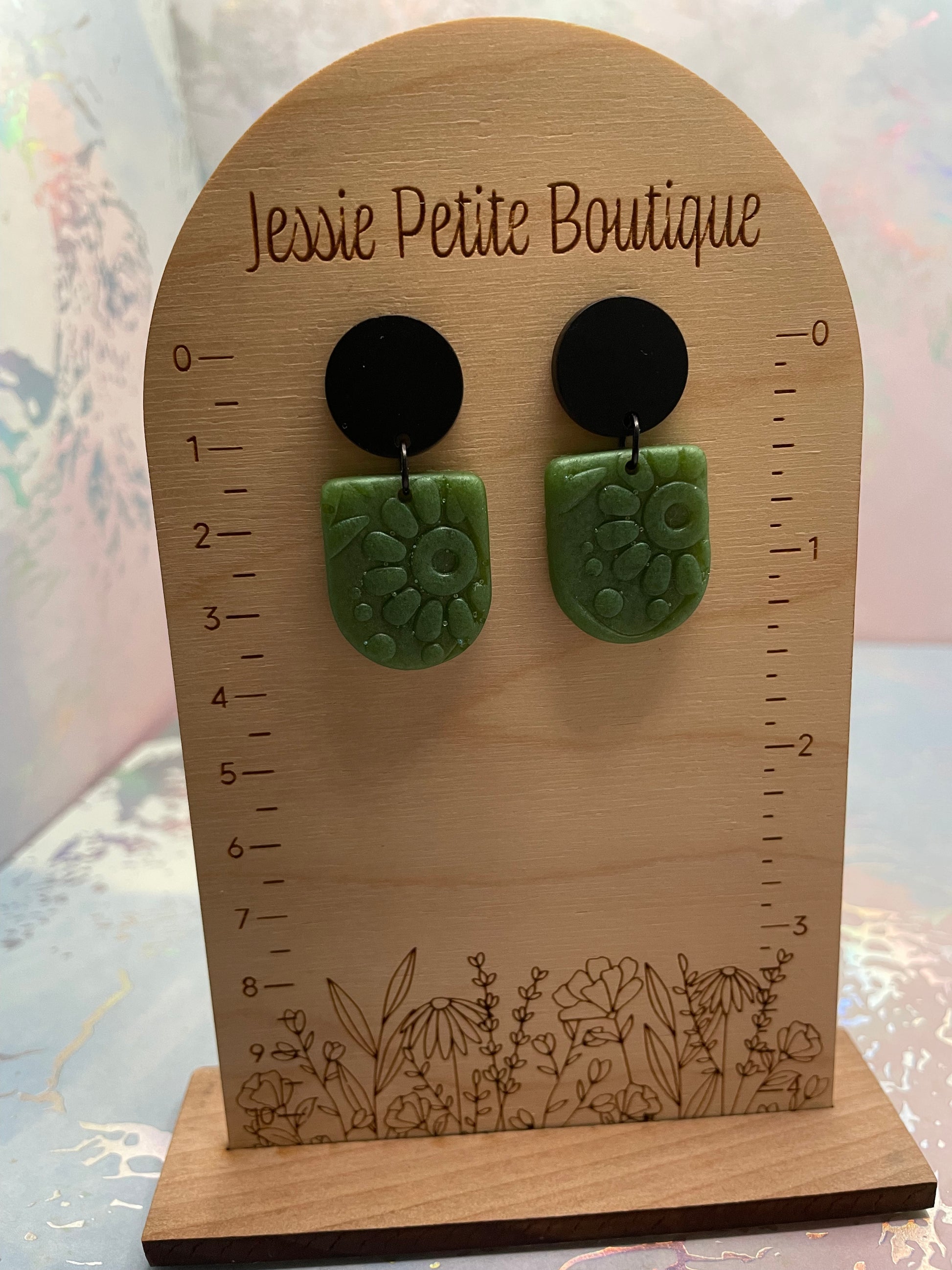 Pair of green and black earrings on a wooden display card with 'Jessie Petite Boutique' branding.