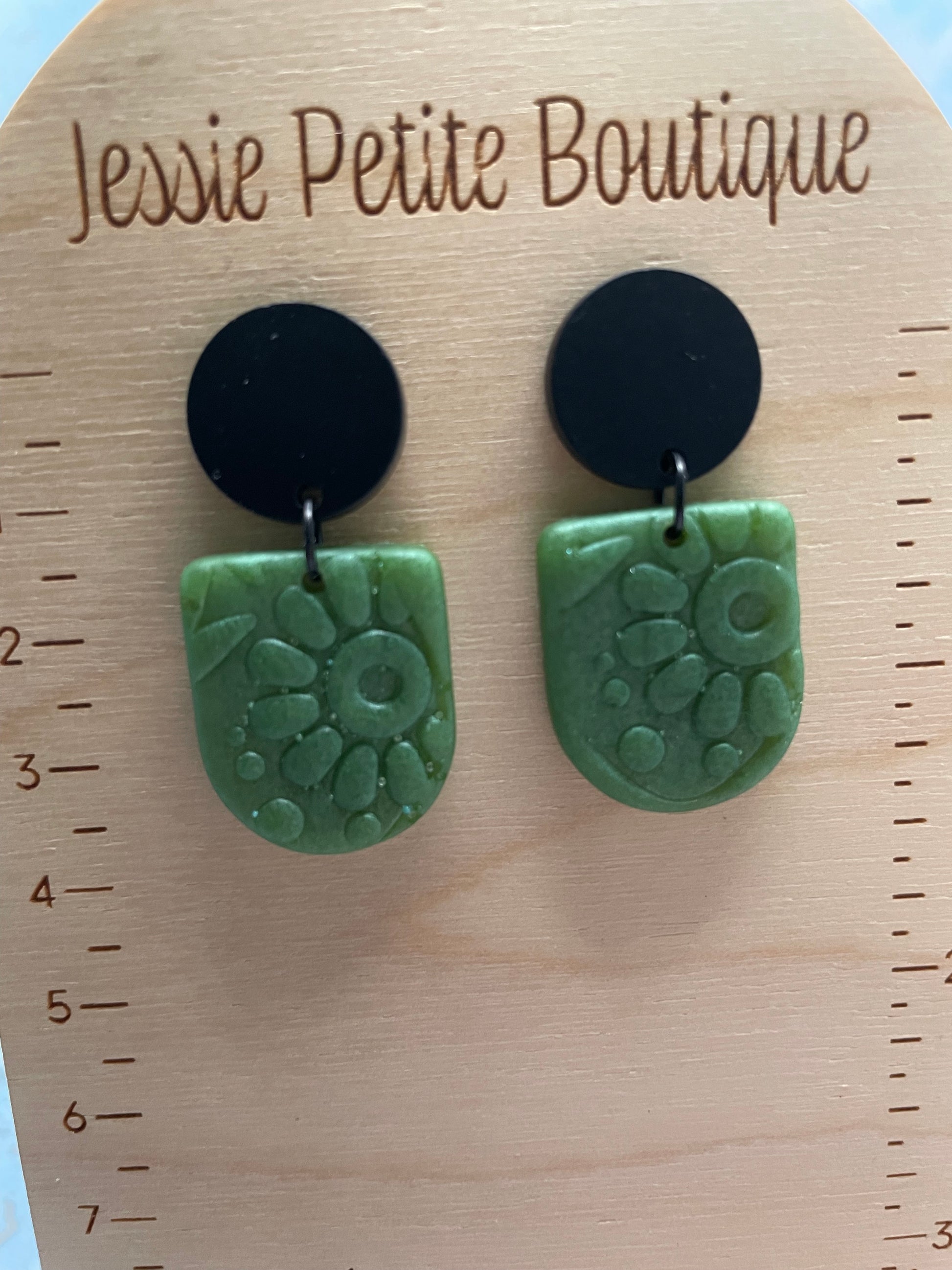 Pair of green and black earrings on a wooden card with 'Jessie Petite Boutique' branding.