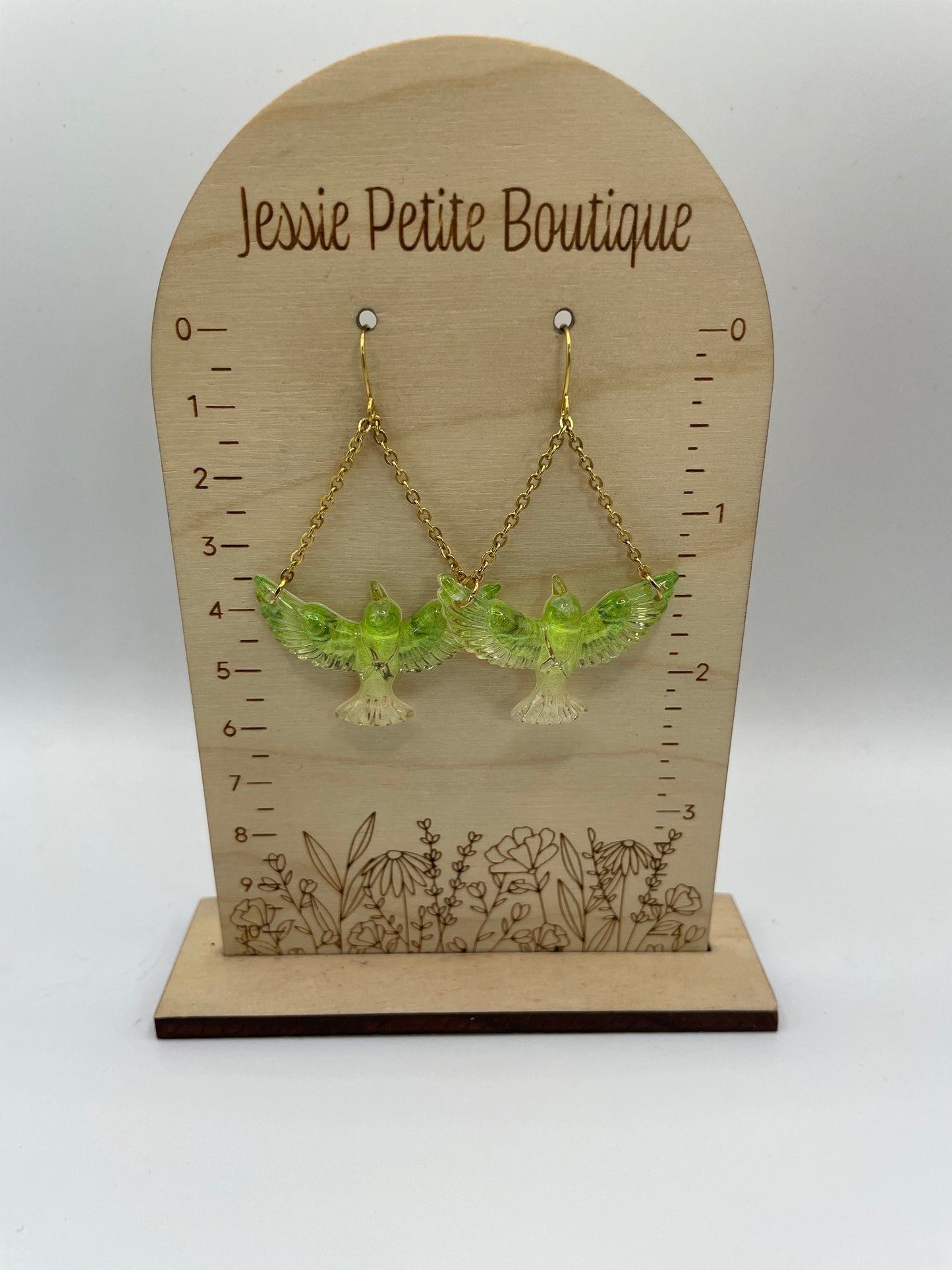 Green earrings on a wooden display card with measurement scale and 'Jessie Petite Boutique' branding.