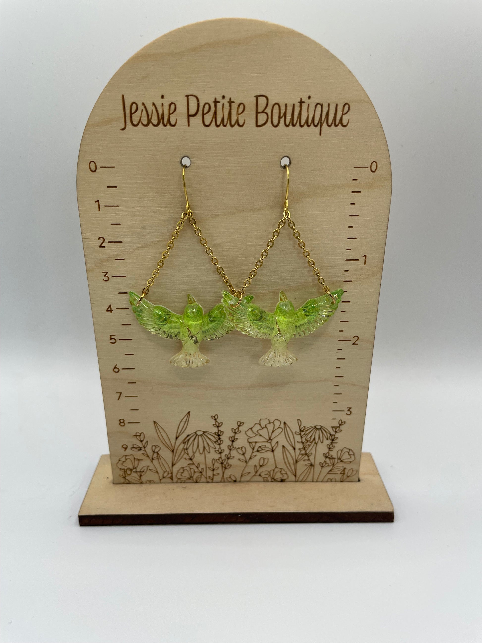 Green earrings on a wooden display card with measurement scale and 'Jessie Petite Boutique' branding.