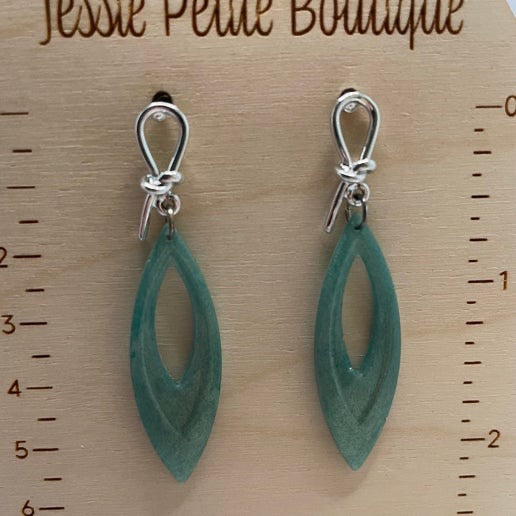Green earrings on a wooden surface with measurement scale, branded 'Jessie Petite Boutique'.