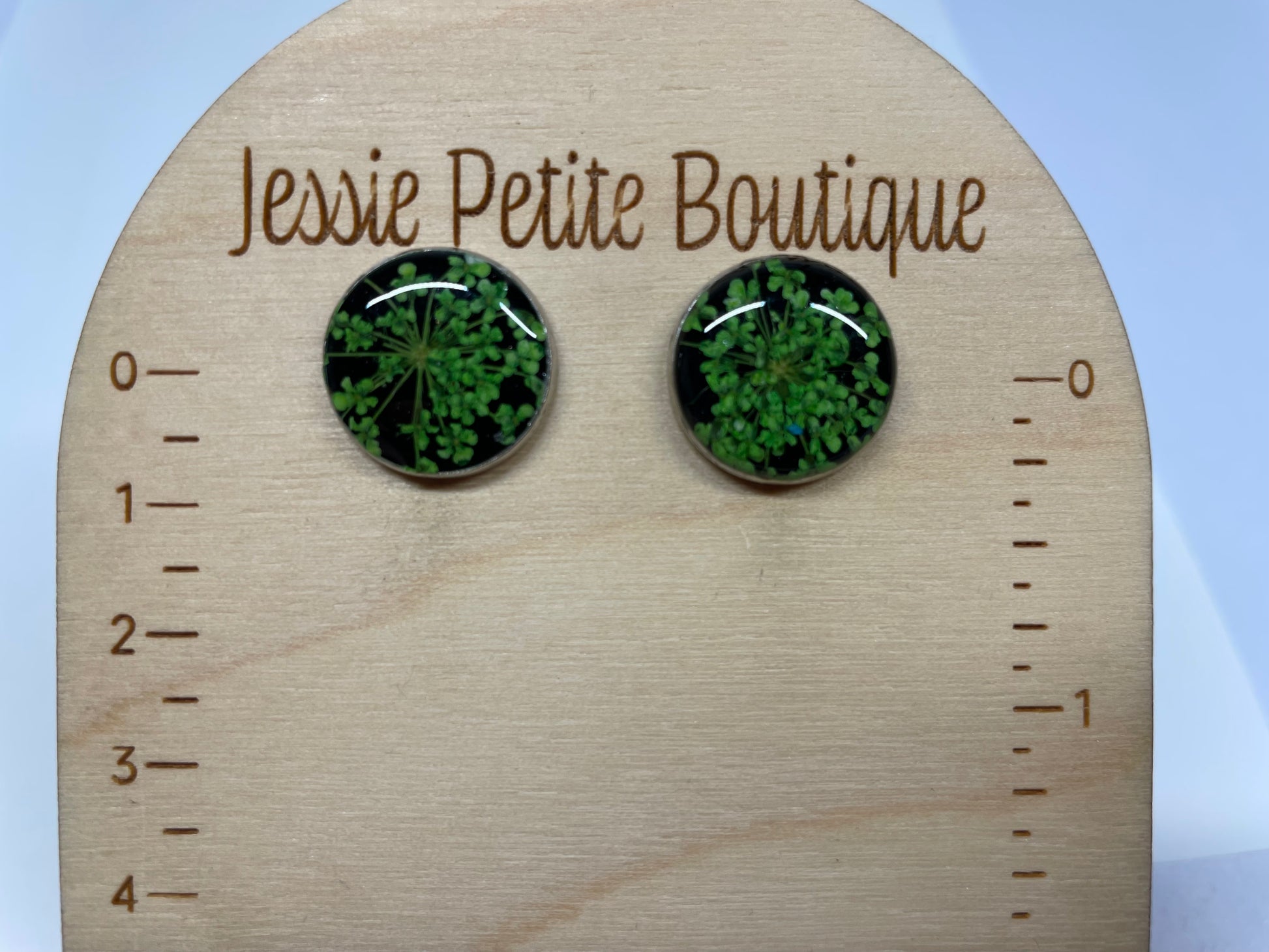 Green floral stud earrings on a wooden display card with 'Jessie Petite Boutique' branding.