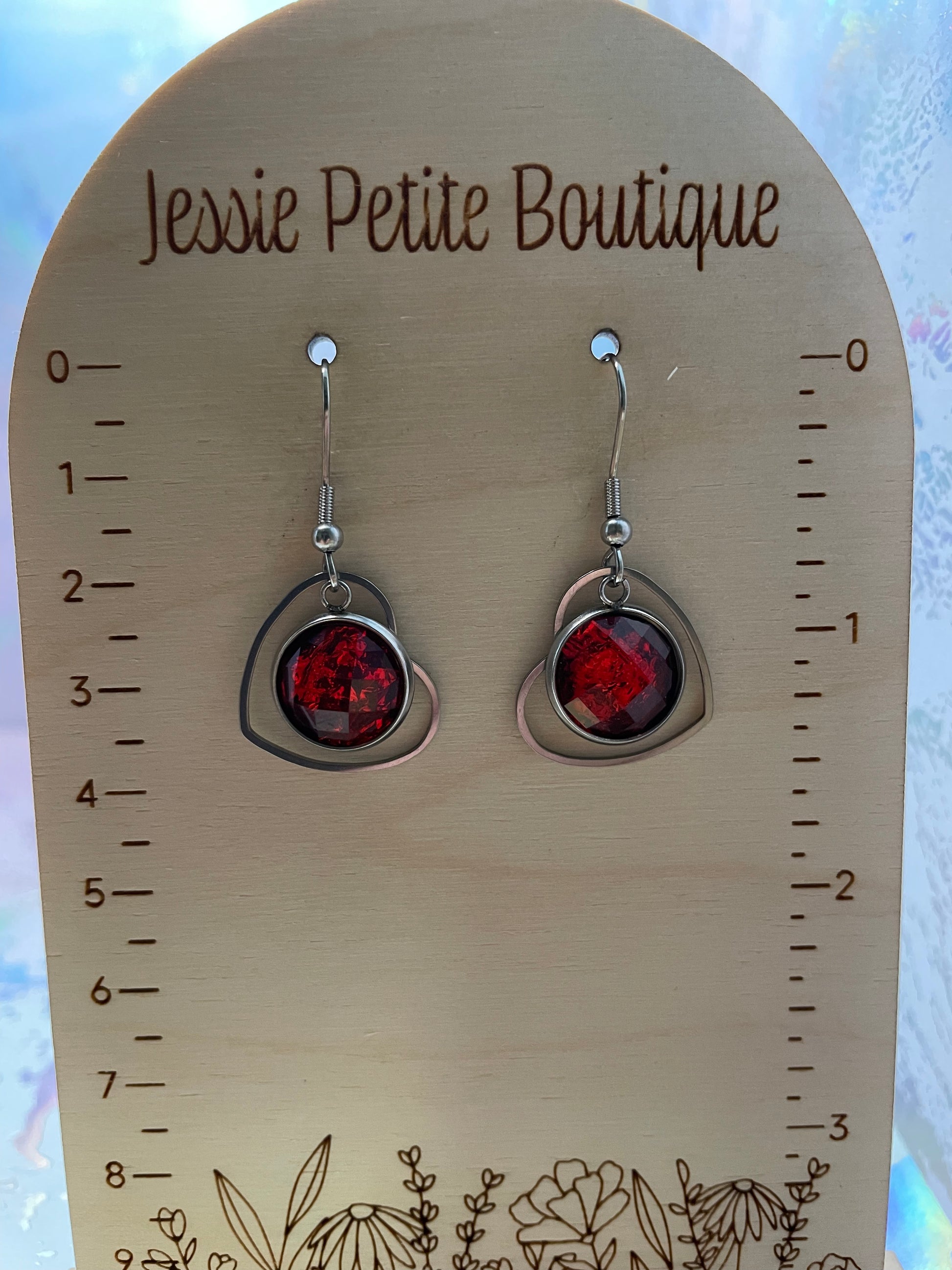 Red earrings on a wooden display card with measurements and 'Jessie Petite Boutique' branding.