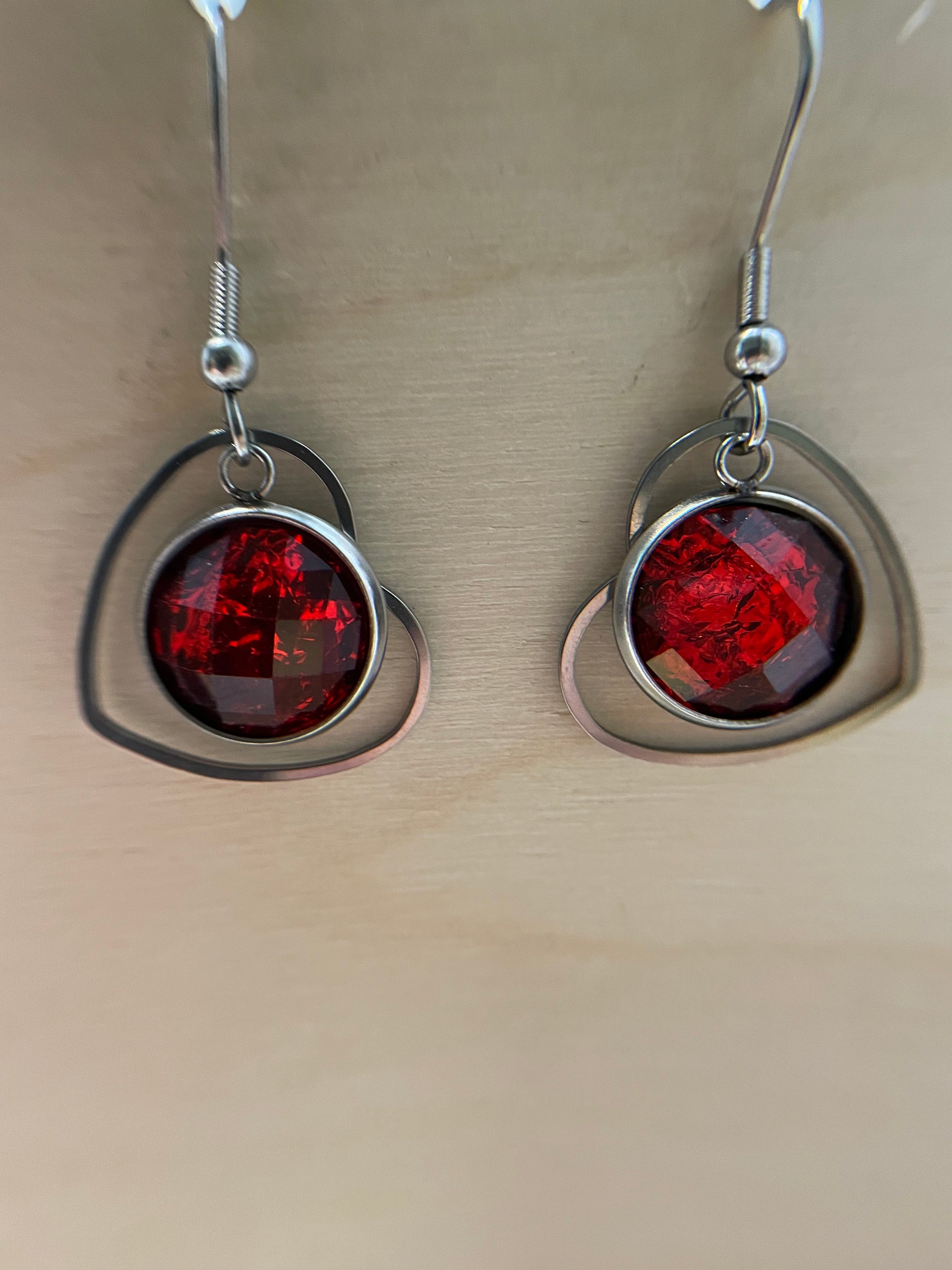 Pair of earrings with red gemstones on a beige background