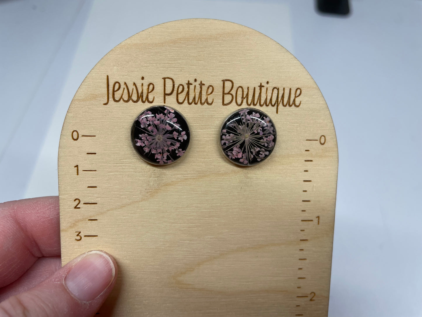 Round earrings with floral design on a wooden display card with 'Jessie Petite Boutique' branding.