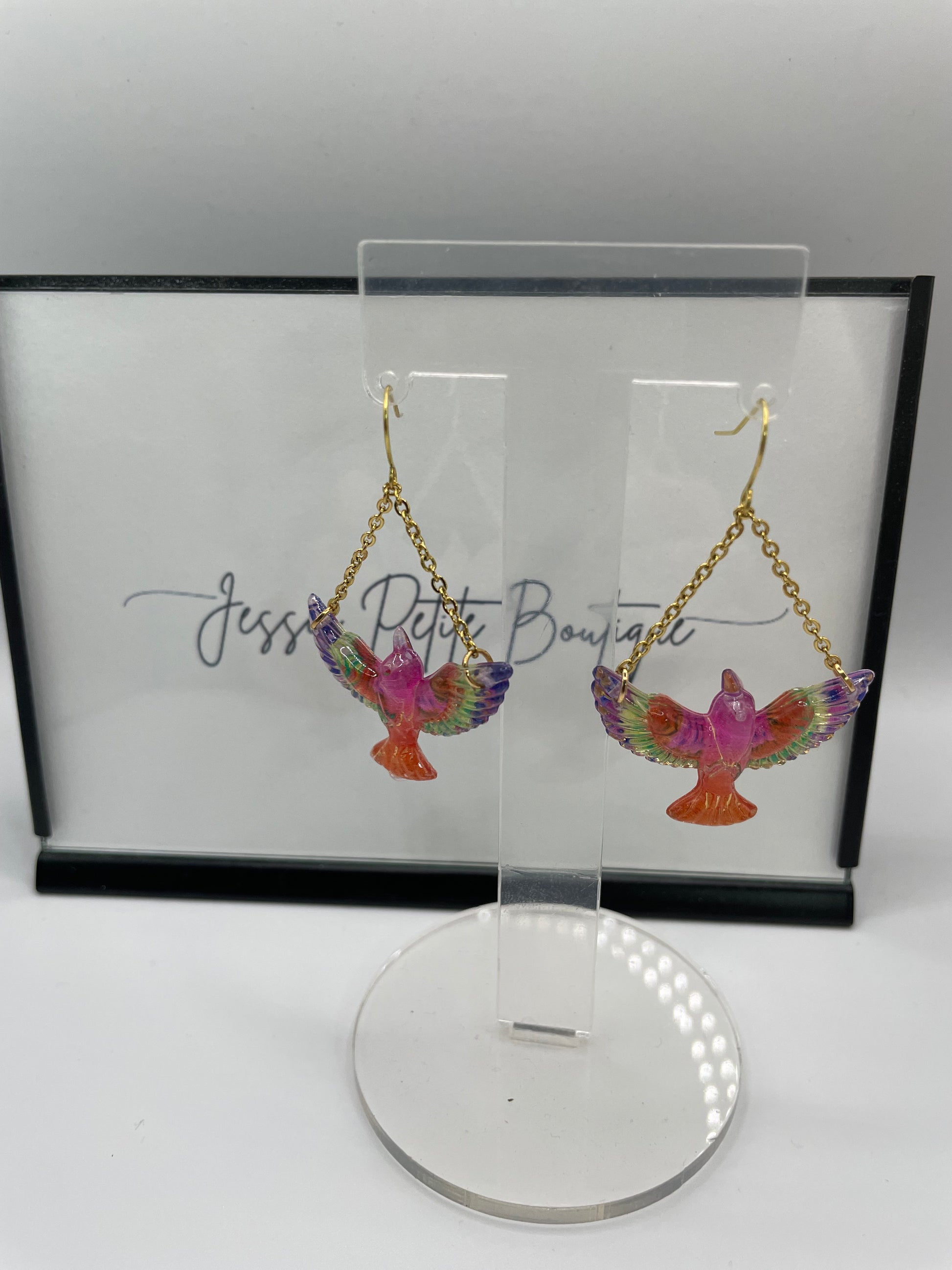 Colorful bird-shaped earrings on a display card branding.