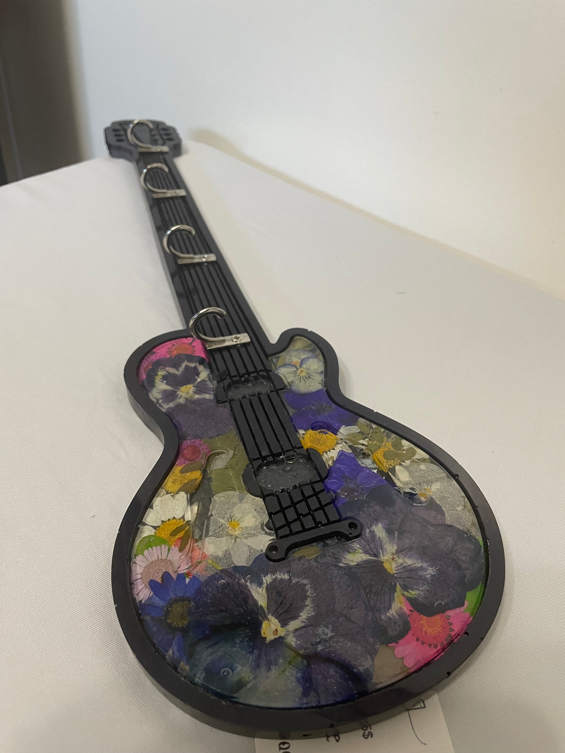 Decorative guitar-shaped pillow with floral pattern on a white background