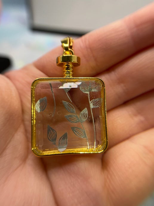 Gold pendant with leaf design held in a hand