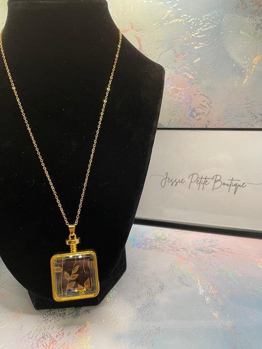 Gold necklace with a square pendant on a black mannequin bust.