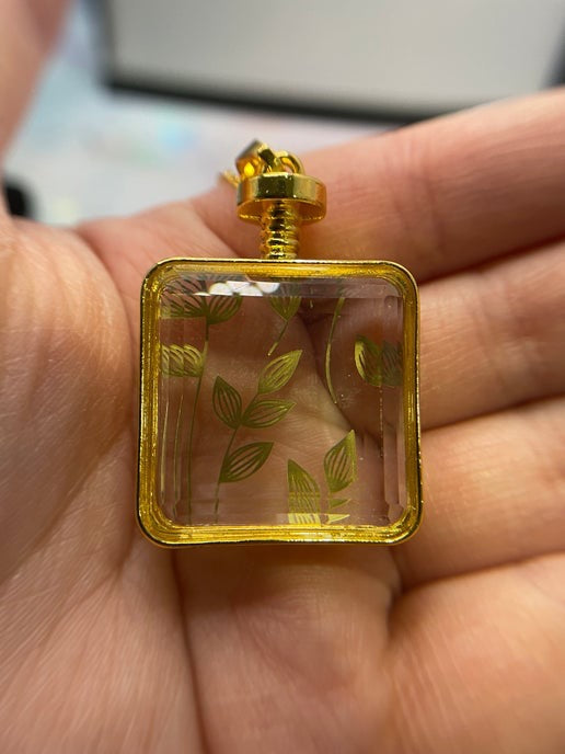 Small square perfume bottle with gold accents held in a hand
