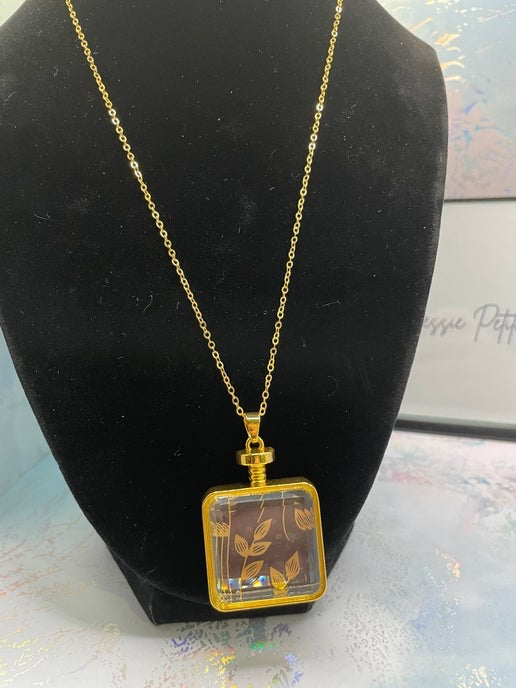 Gold necklace with a square pendant on a black bust