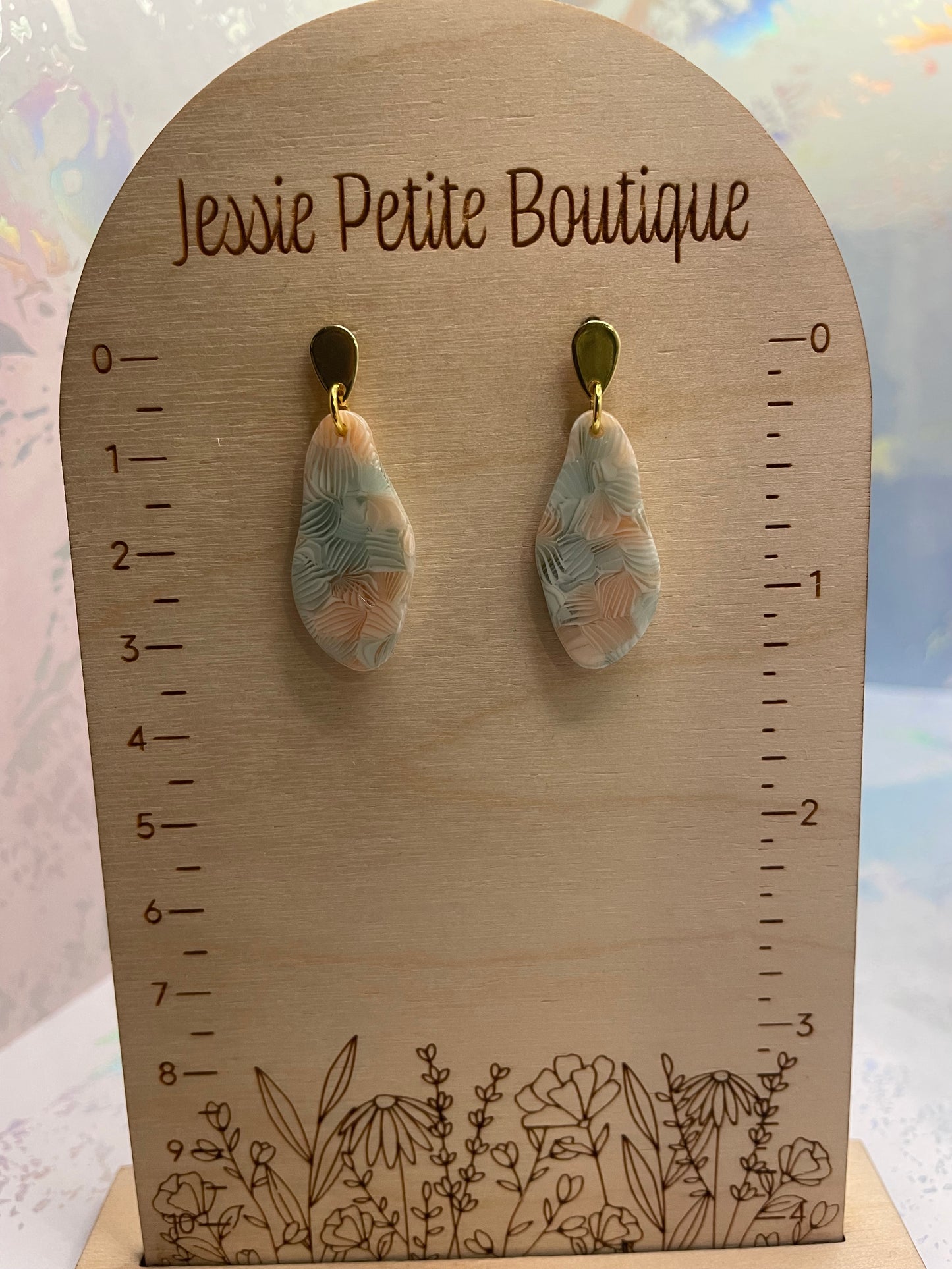 Teardrop-shaped earrings on a wooden card with measurements and floral design, branded 'Jessie Petite Boutique'.