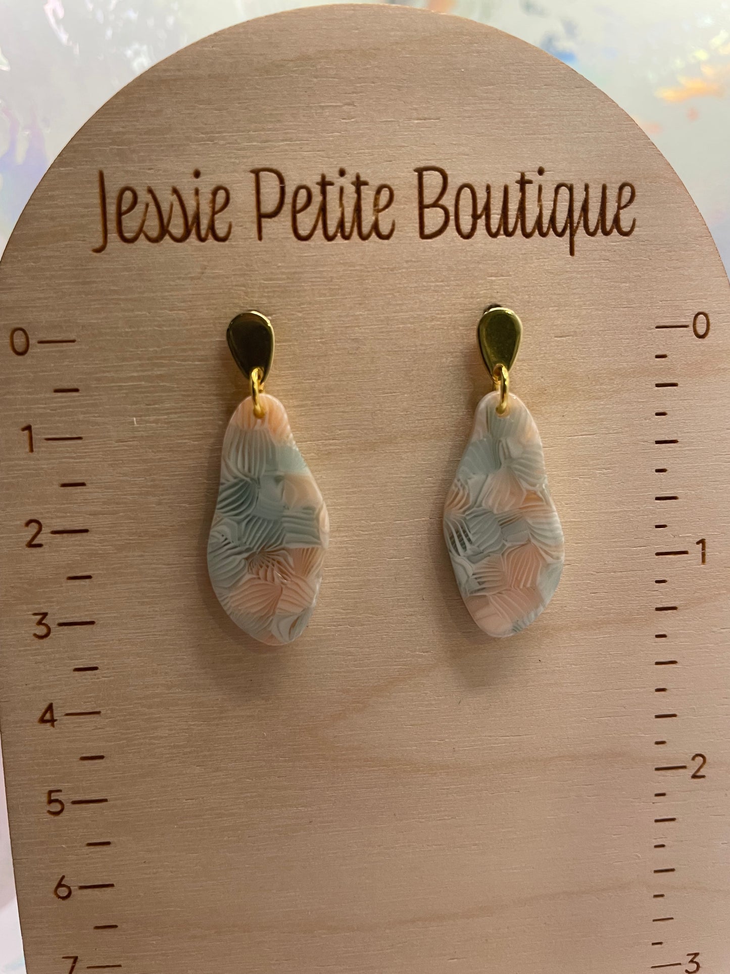 Pair of earrings on a wooden display card with 'Jessie Petite Boutique' branding.