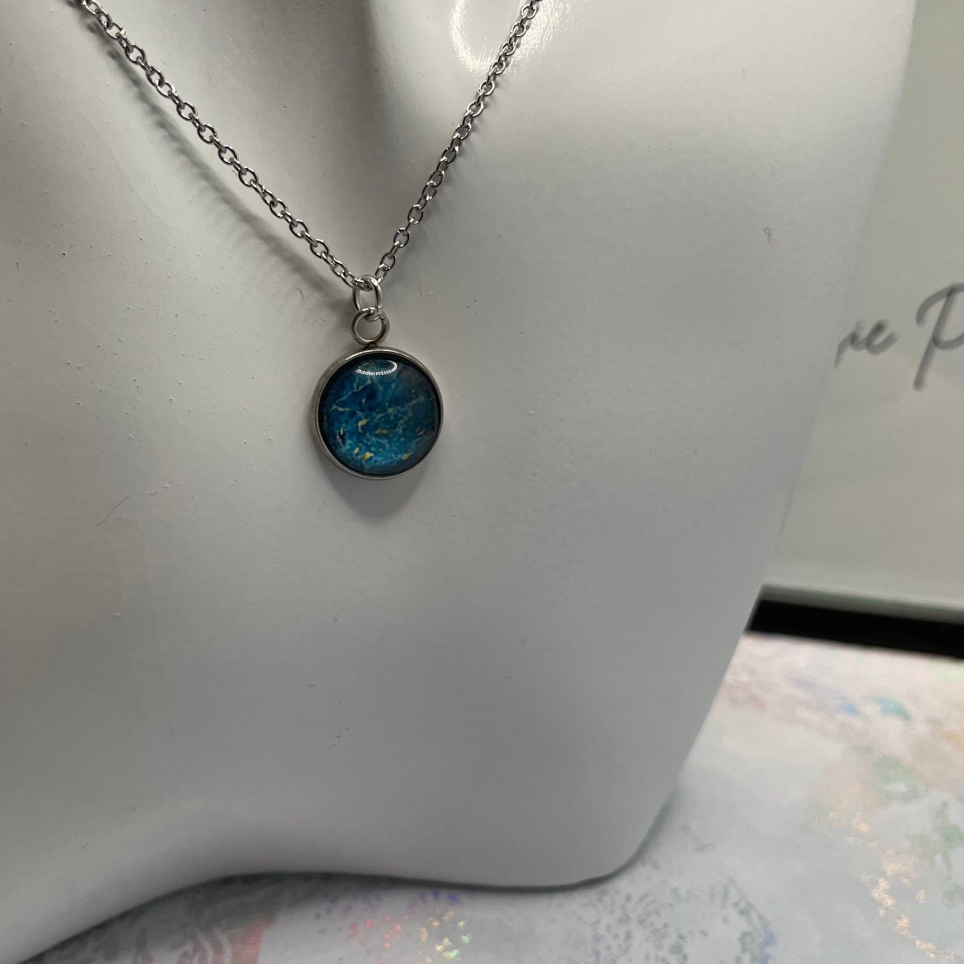 Necklace with a blue pendant on a mannequin bust.