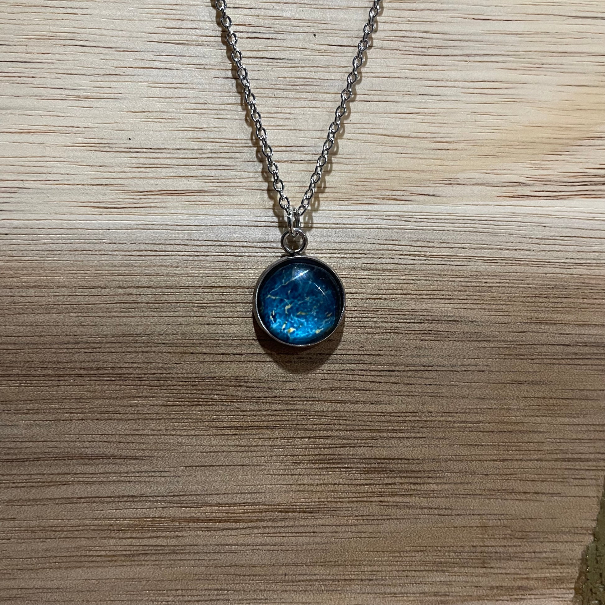 Necklace with a blue pendant on a wooden surface