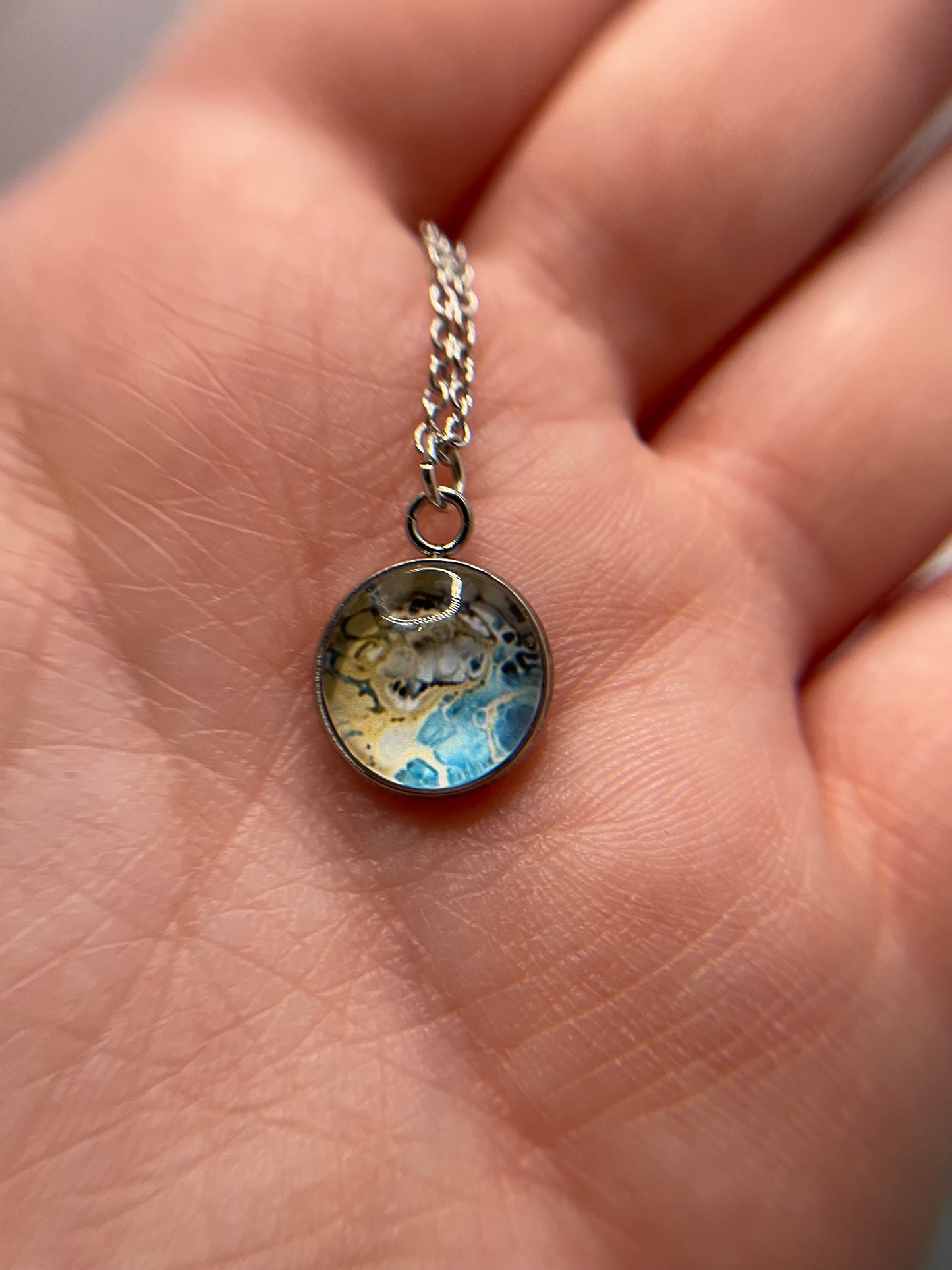 Necklace with a round pendant featuring a dog's face held in a hand.