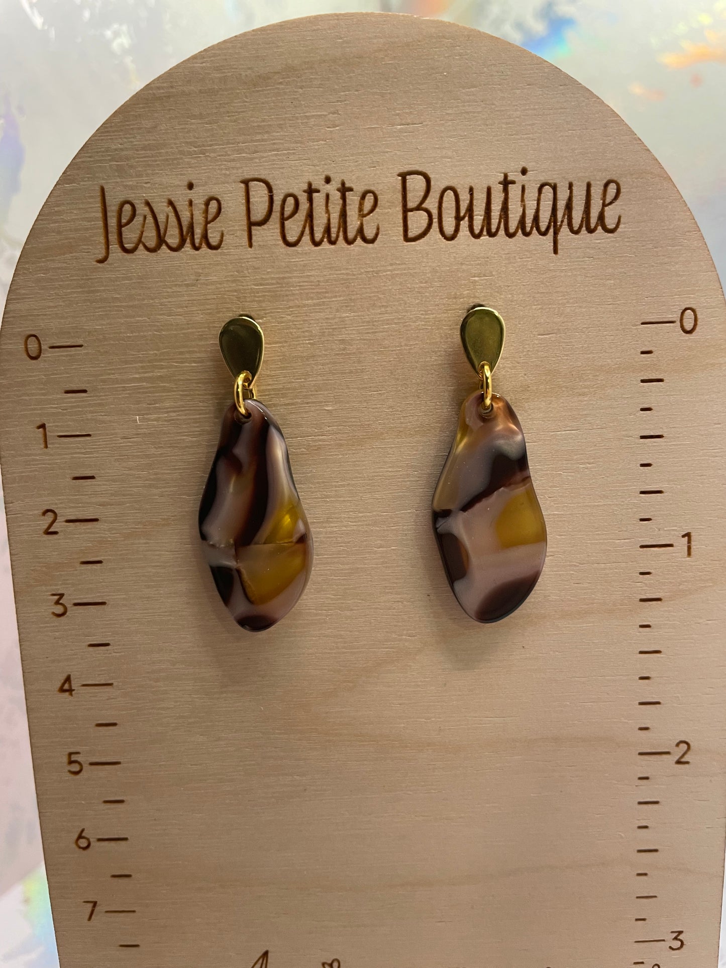 Pair of teardrop-shaped earrings on a wooden display card with 'Jessie Petite Boutique' branding.
