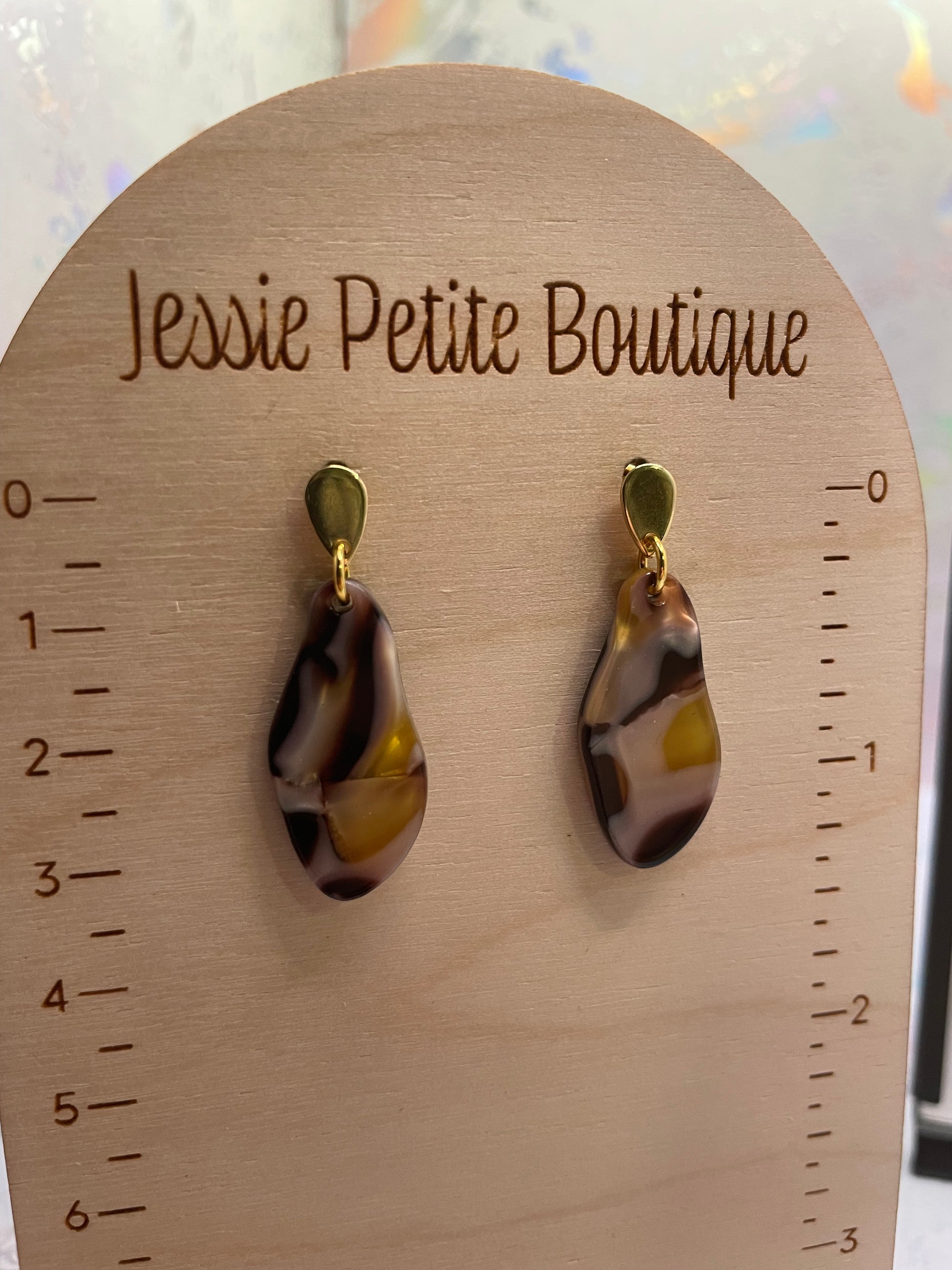 Pair of marbled teardrop earrings on a wooden card with measurements, branded 'Jessie Petite Boutique'.