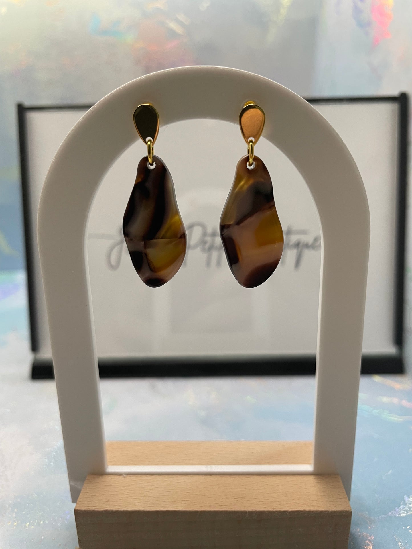 Pair of brown earrings on a white stand with a blurred background