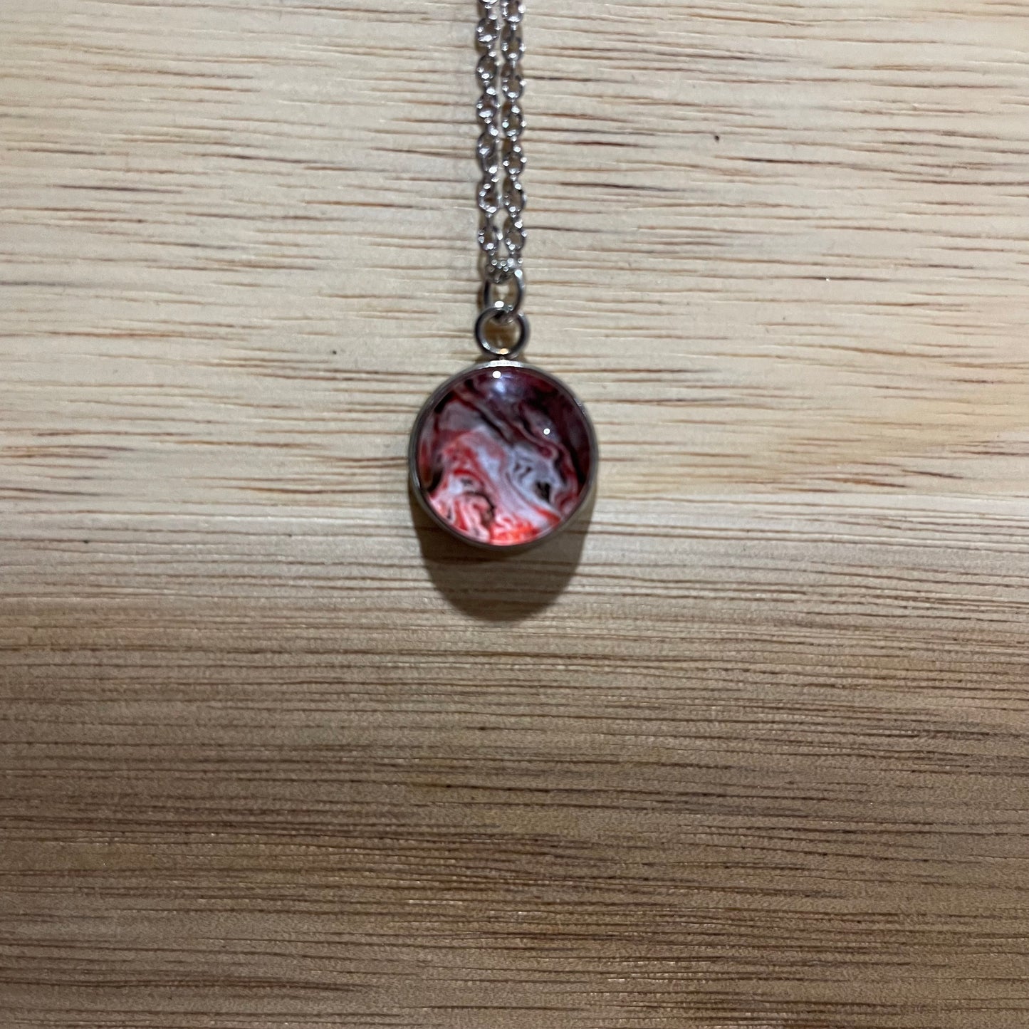 Necklace with a marbled pendant on a wooden surface