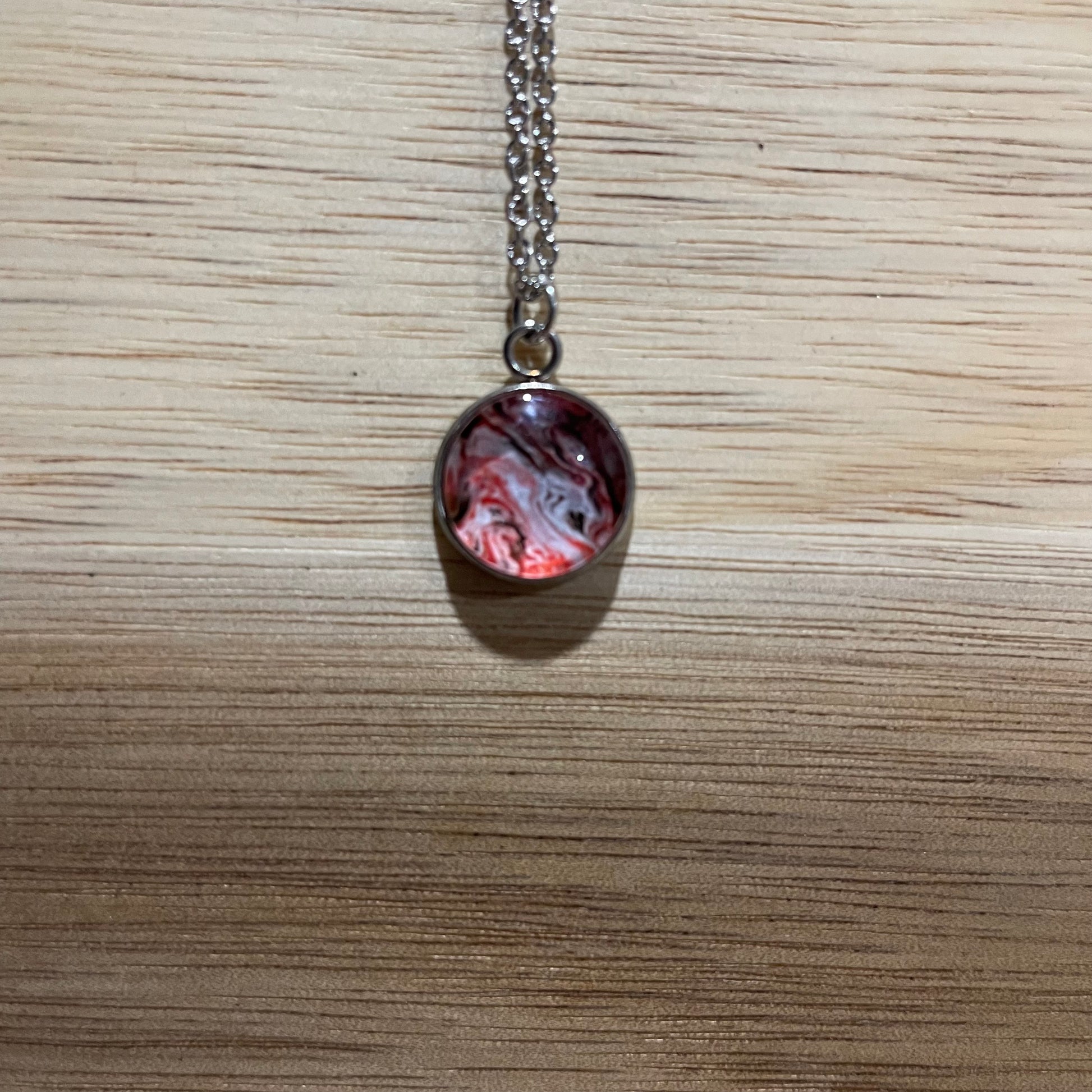 Necklace with a marbled pendant on a wooden surface