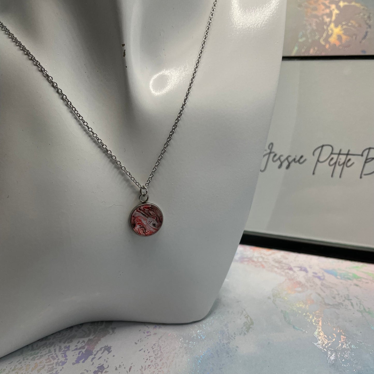 Necklace with a marbled pendant on a mannequin bust, with 'Jessie Petite Boutique' branding in the background.