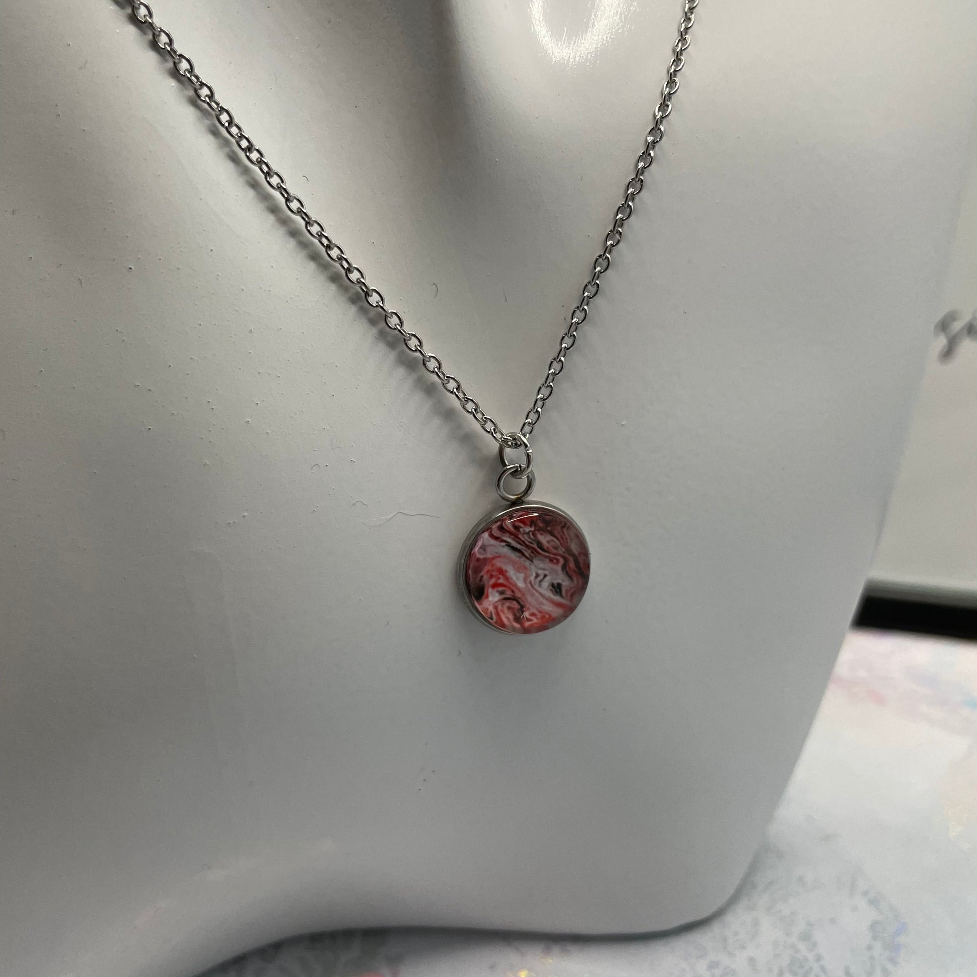 Necklace with a marbled pendant on a mannequin bust.