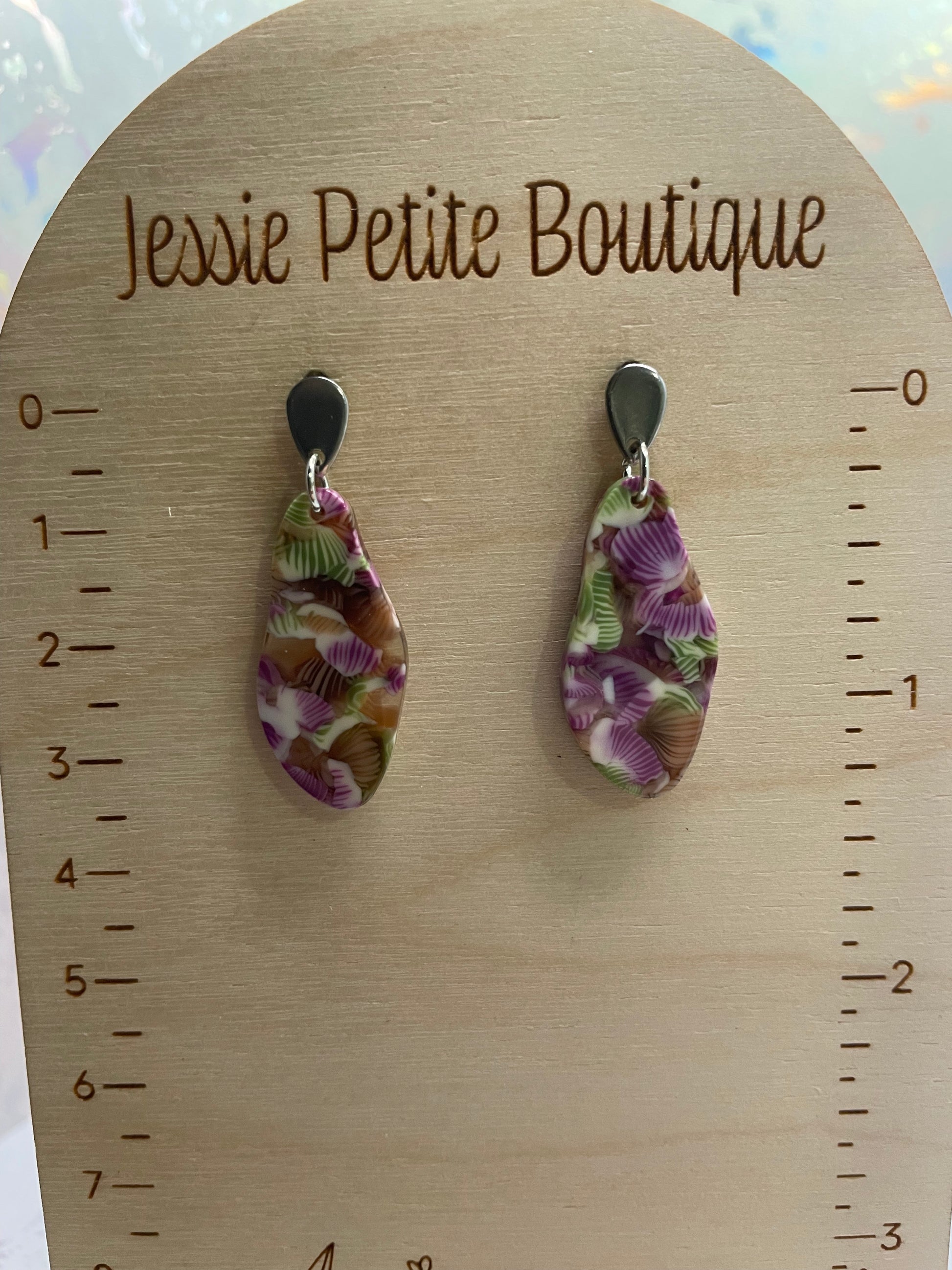 patterned earrings on a wooden display card with measurement scale.