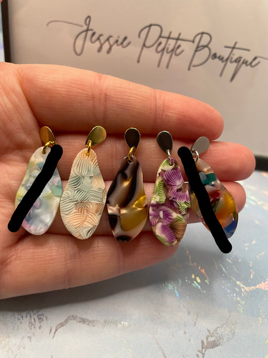 Colourful earrings held in a hand with a blurred background