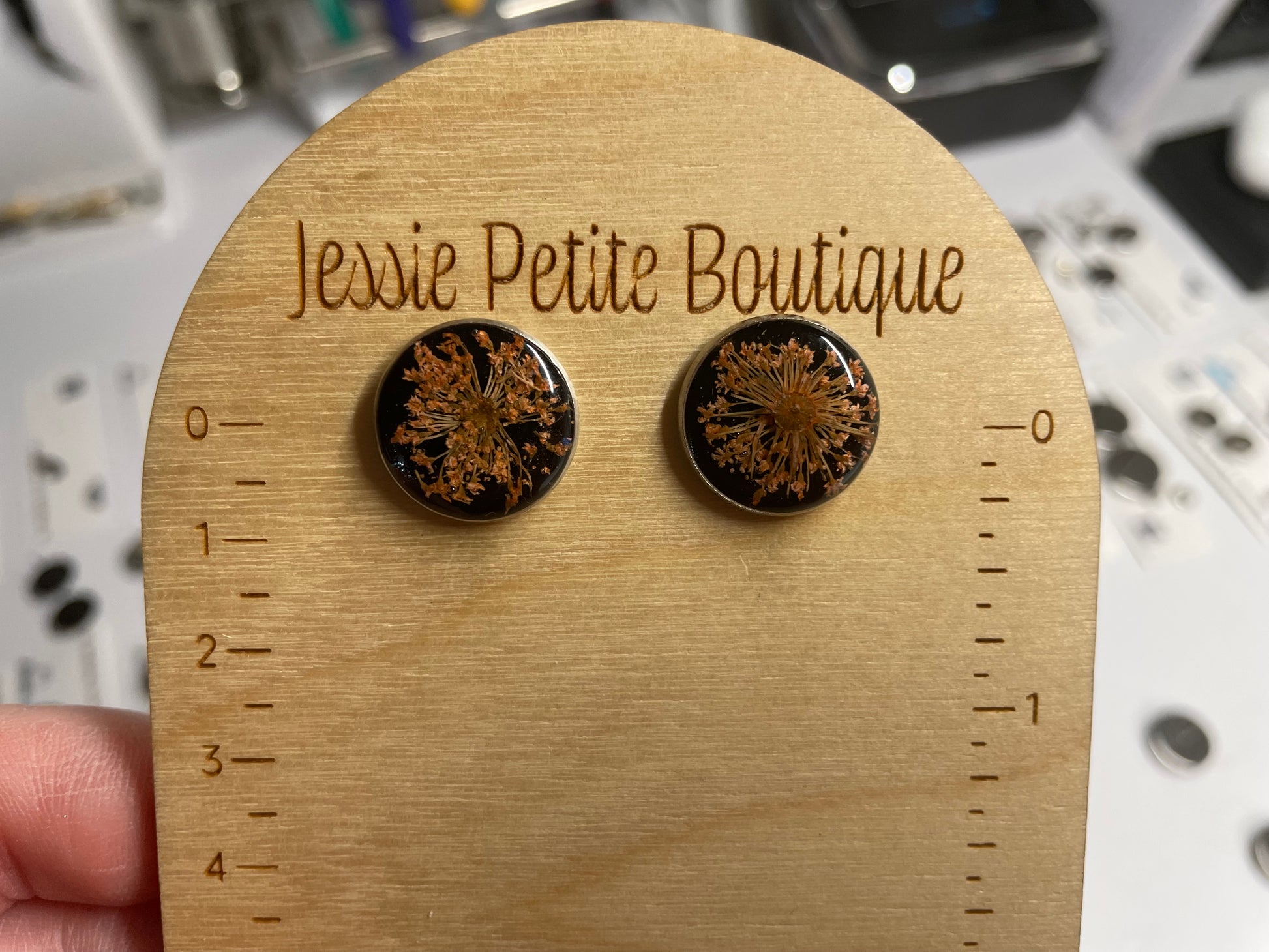 Pair of floral earrings on a wooden display card with 'Jessie Petite Boutique' branding.