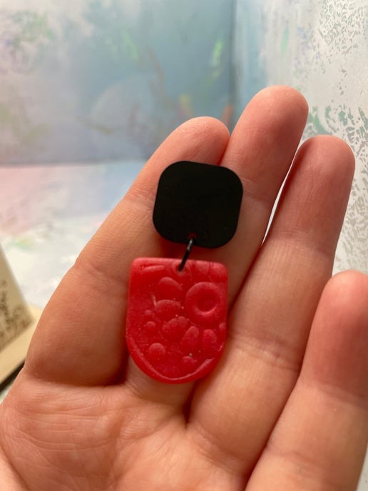 pink and black pendant held in a hand with a blurred background