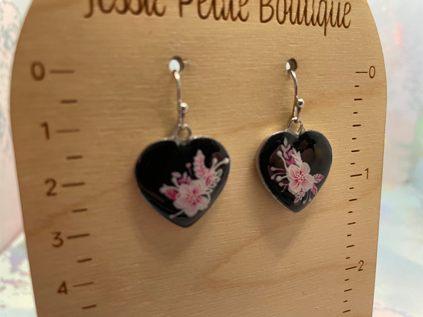 Heart-shaped earrings with floral design on a wooden card with measurements.