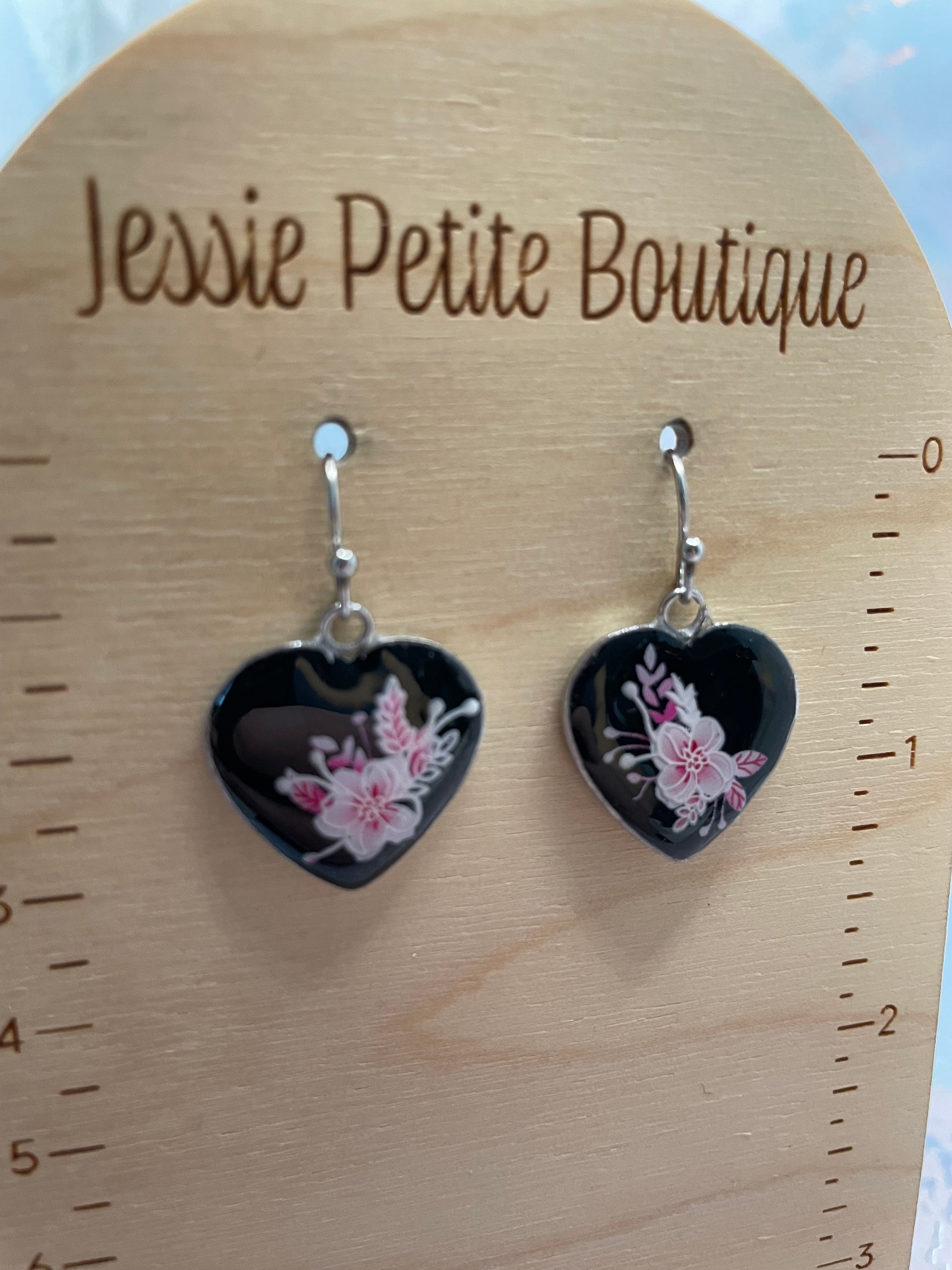 Heart-shaped earrings with floral design on a wooden card with 'Jessie Petite Boutique' branding.