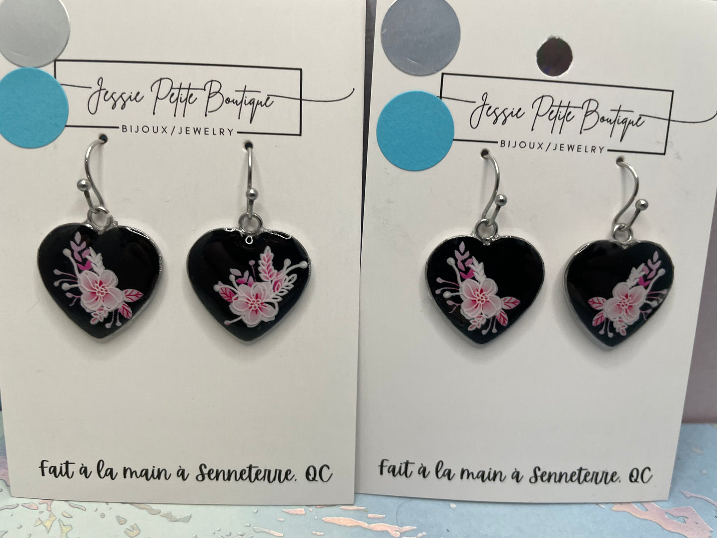 Heart-shaped earrings with floral design on a branded card, displayed twice.