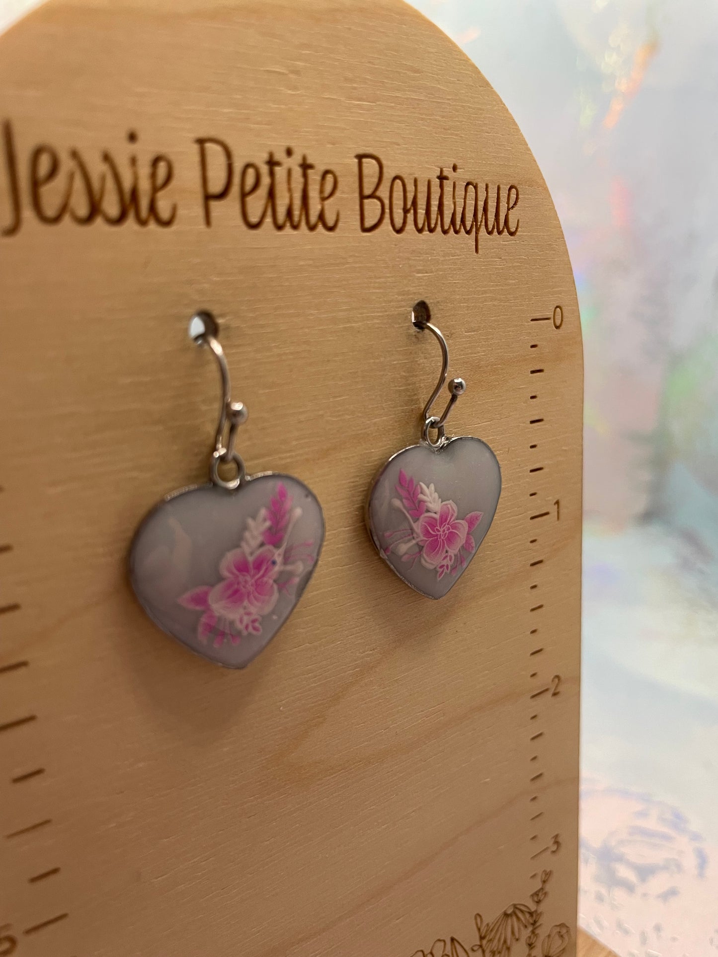 Heart-shaped earrings with floral design on a wooden card with 'Jessie Petite Boutique' branding.