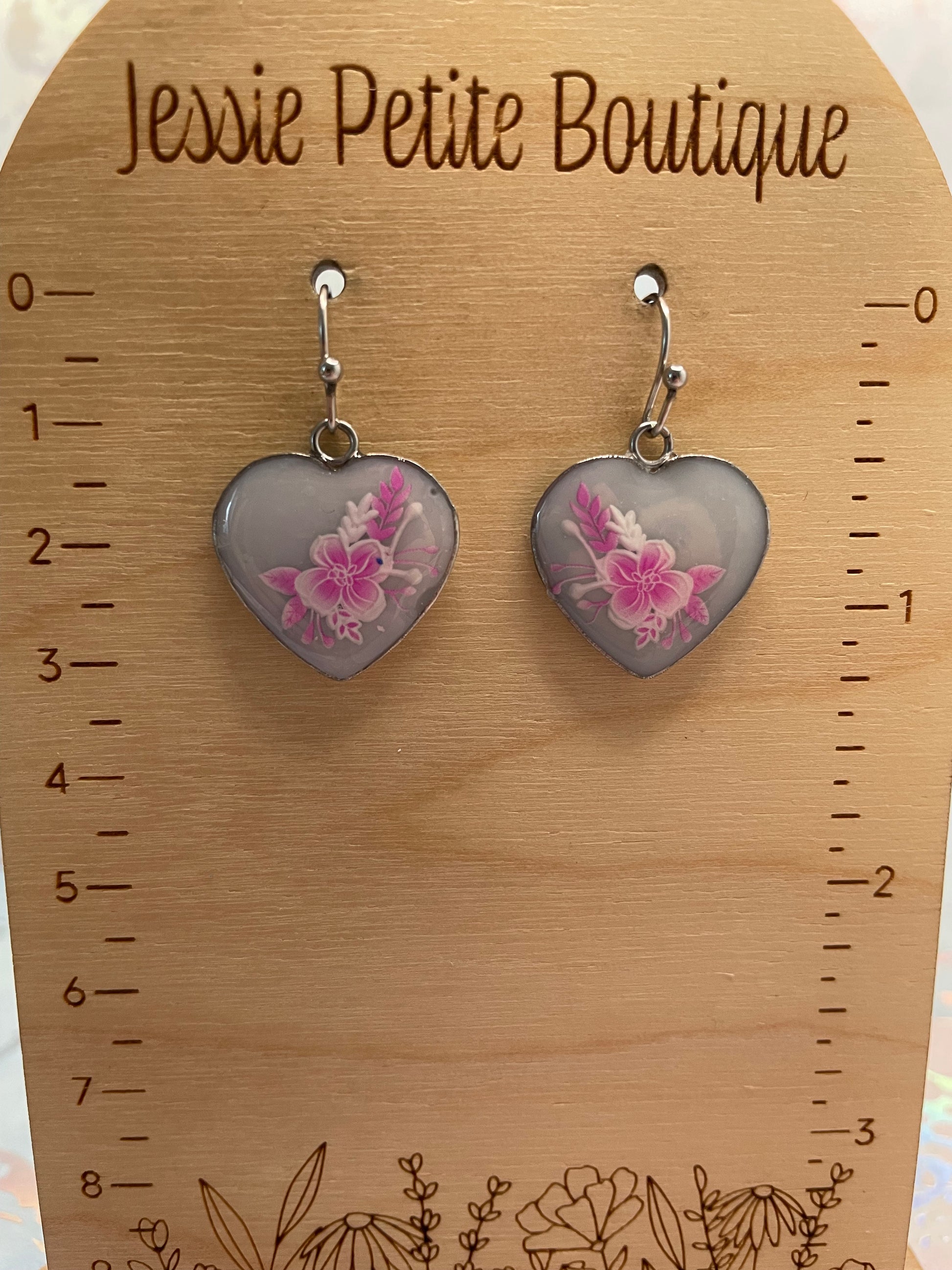 Heart-shaped earrings with floral design on a wooden card with measurement scale and 'Jessie Petite Boutique' branding.