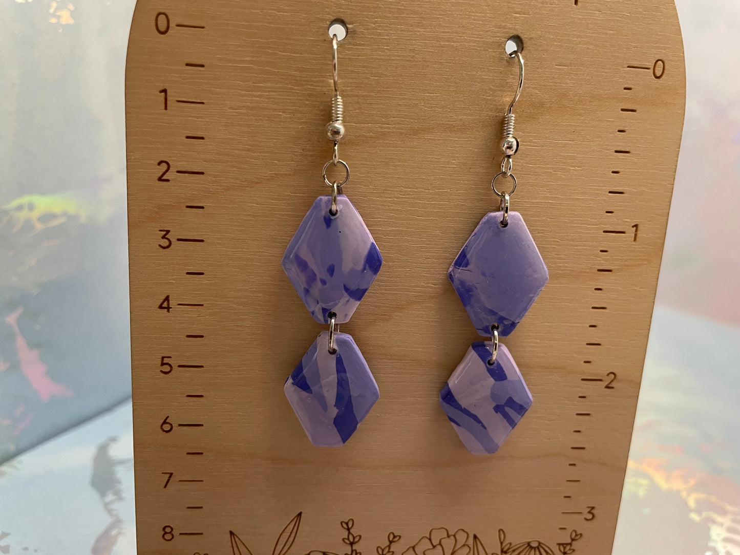 Pair of purple geometric earrings on a wooden ruler