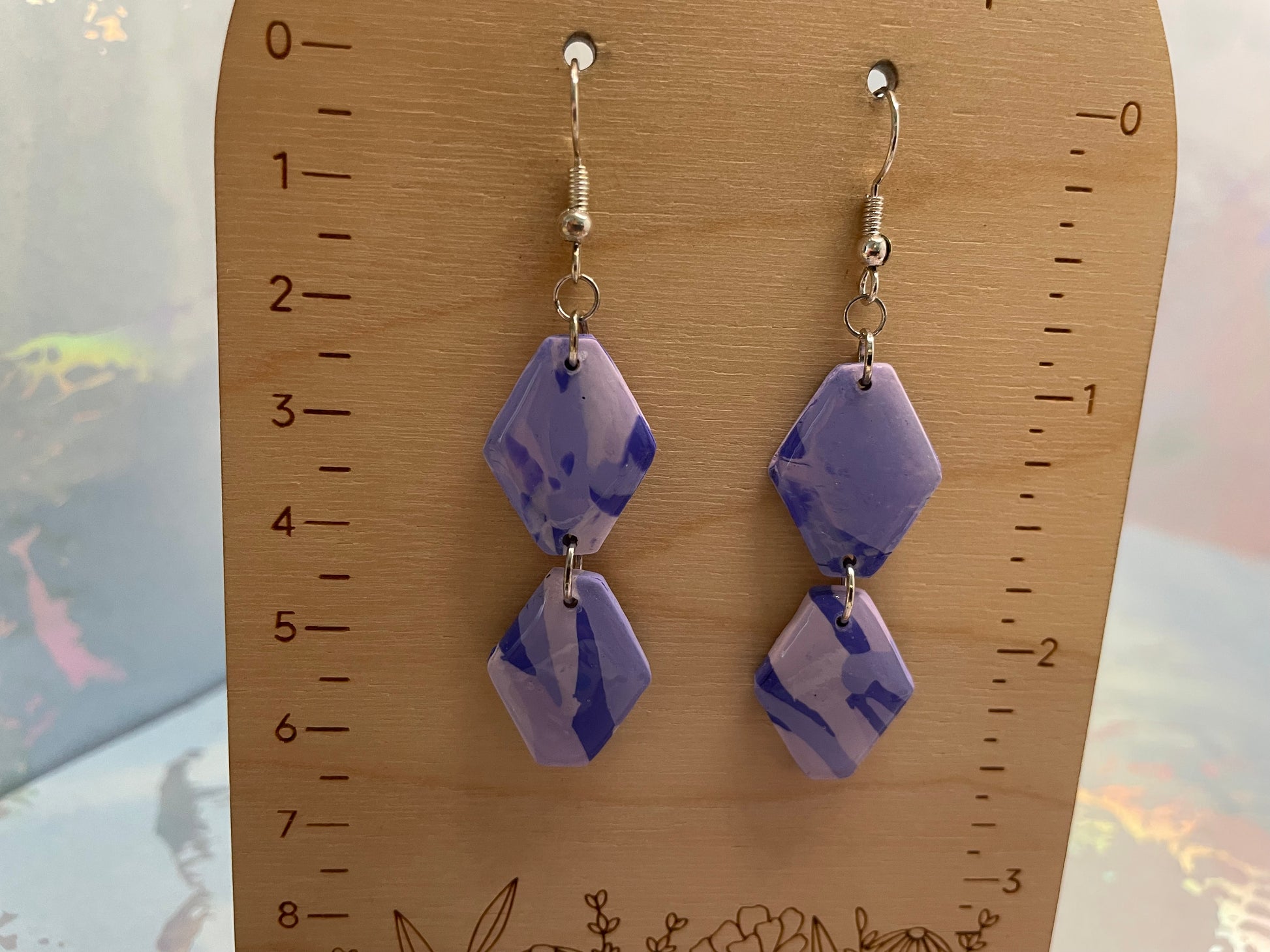 Pair of purple geometric earrings on a wooden ruler