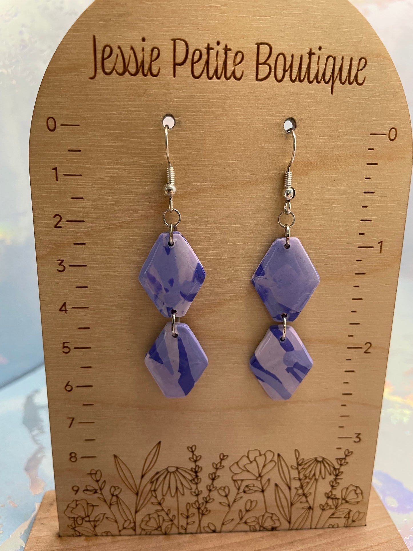 Pair of purple geometric earrings on a wooden card with 'Jessie Petite Boutique' branding.