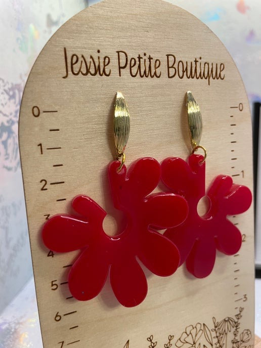 Red flower-shaped earrings on a wooden card with 'Jessie Petite Boutique' branding.