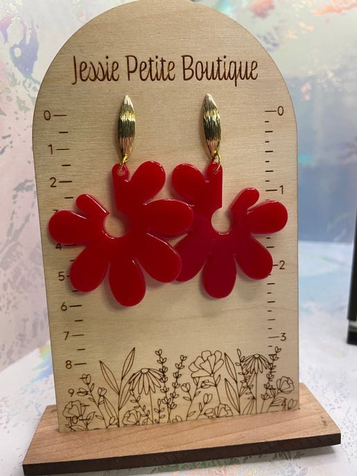 Red flower-shaped earrings on a wooden display card with 'Jessie Petite Boutique' branding.