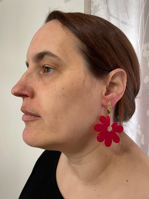 Person wearing a red floral earring with a neutral background