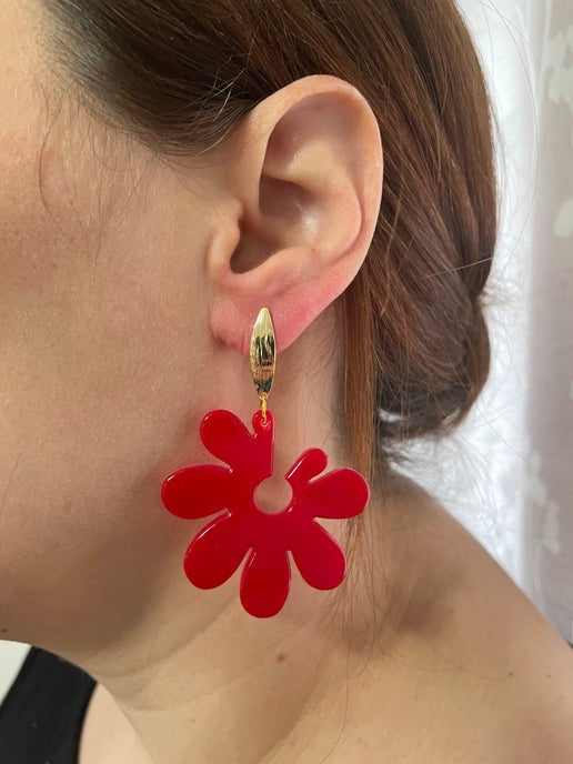 Red floral earring worn by a person with a neutral background