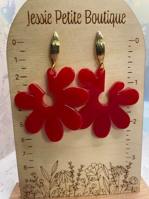 Red flower-shaped earrings on a wooden card with 'Jessie Petite Boutique' branding.