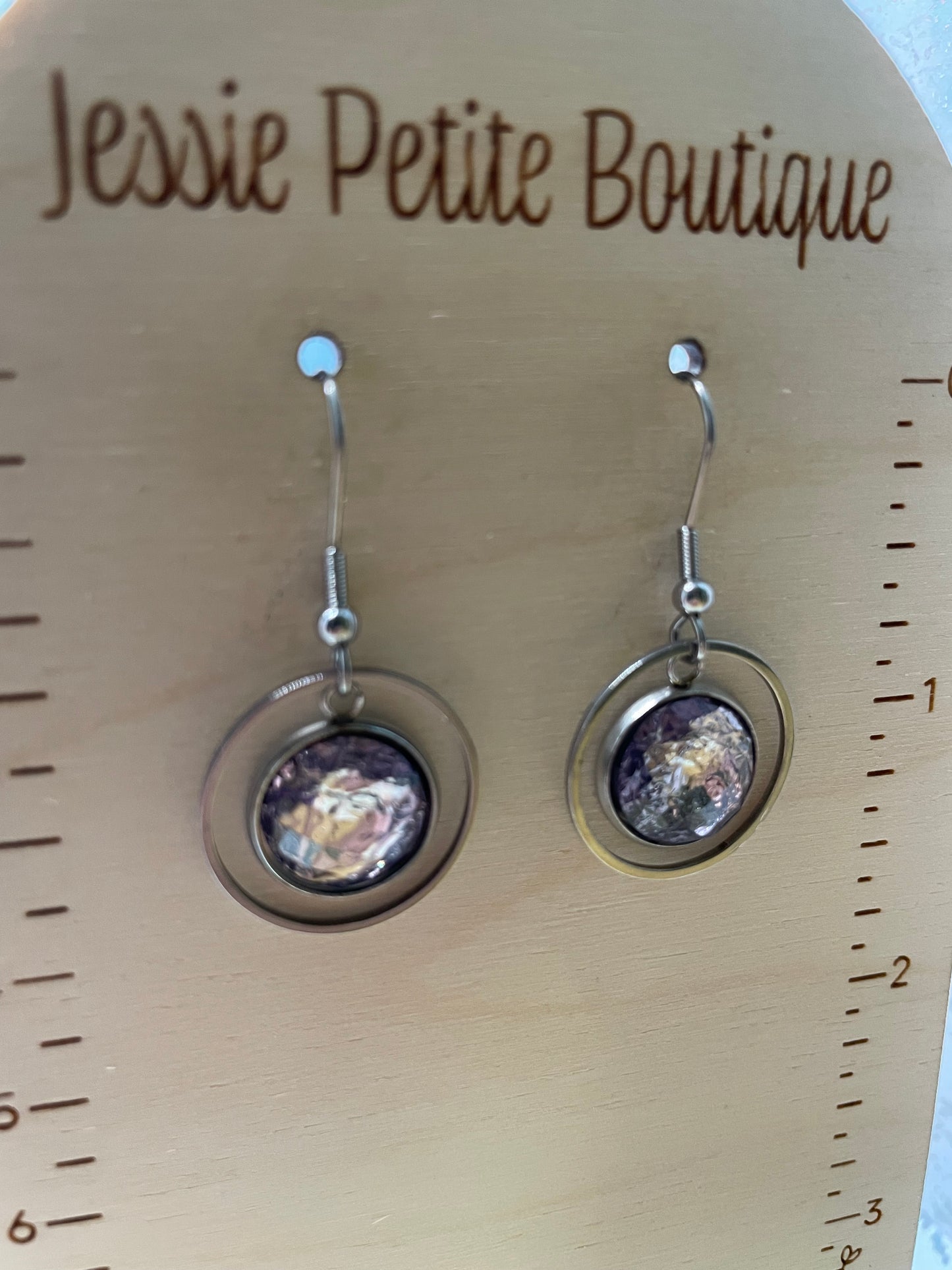 Pair of earrings on a wooden display card with 'Jessie Petite Boutique' branding.