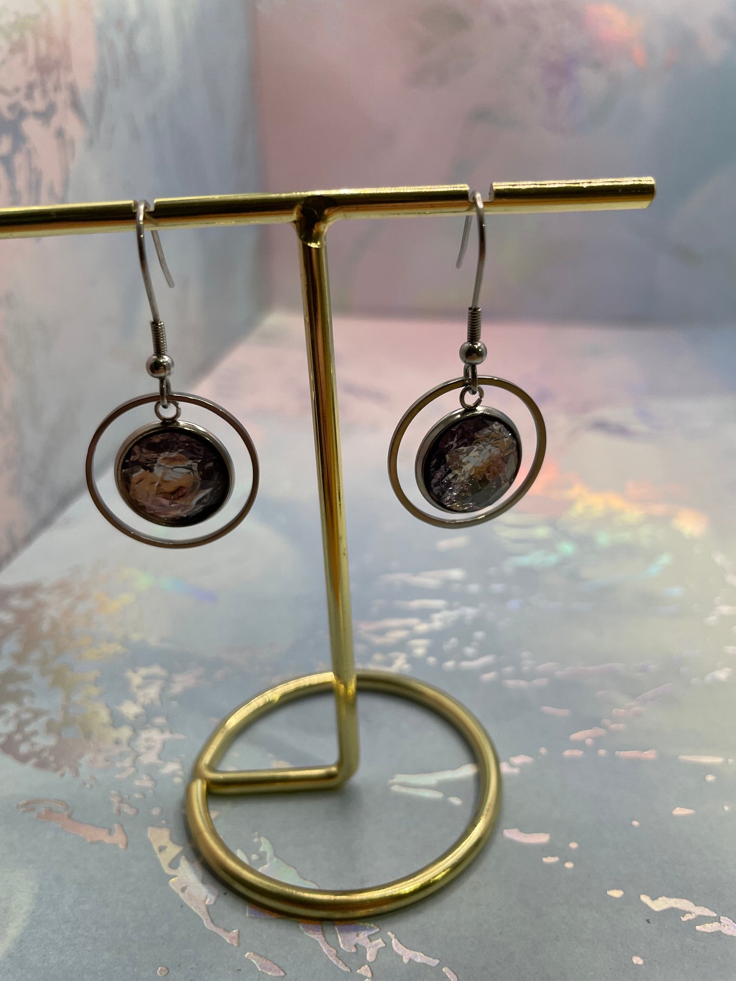 Pair of silver earrings with circular designs on a reflective surface