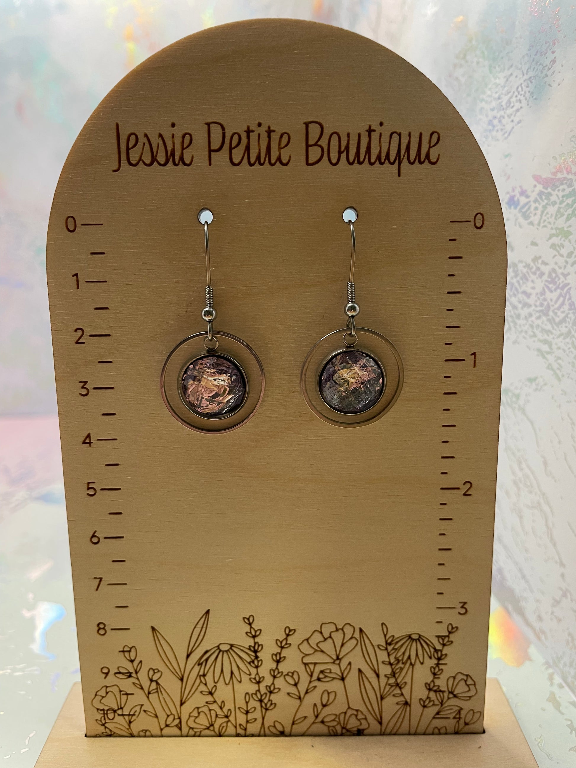 Pair of earrings on a wooden display card with floral designs and 'Jessie Petite Boutique' branding.